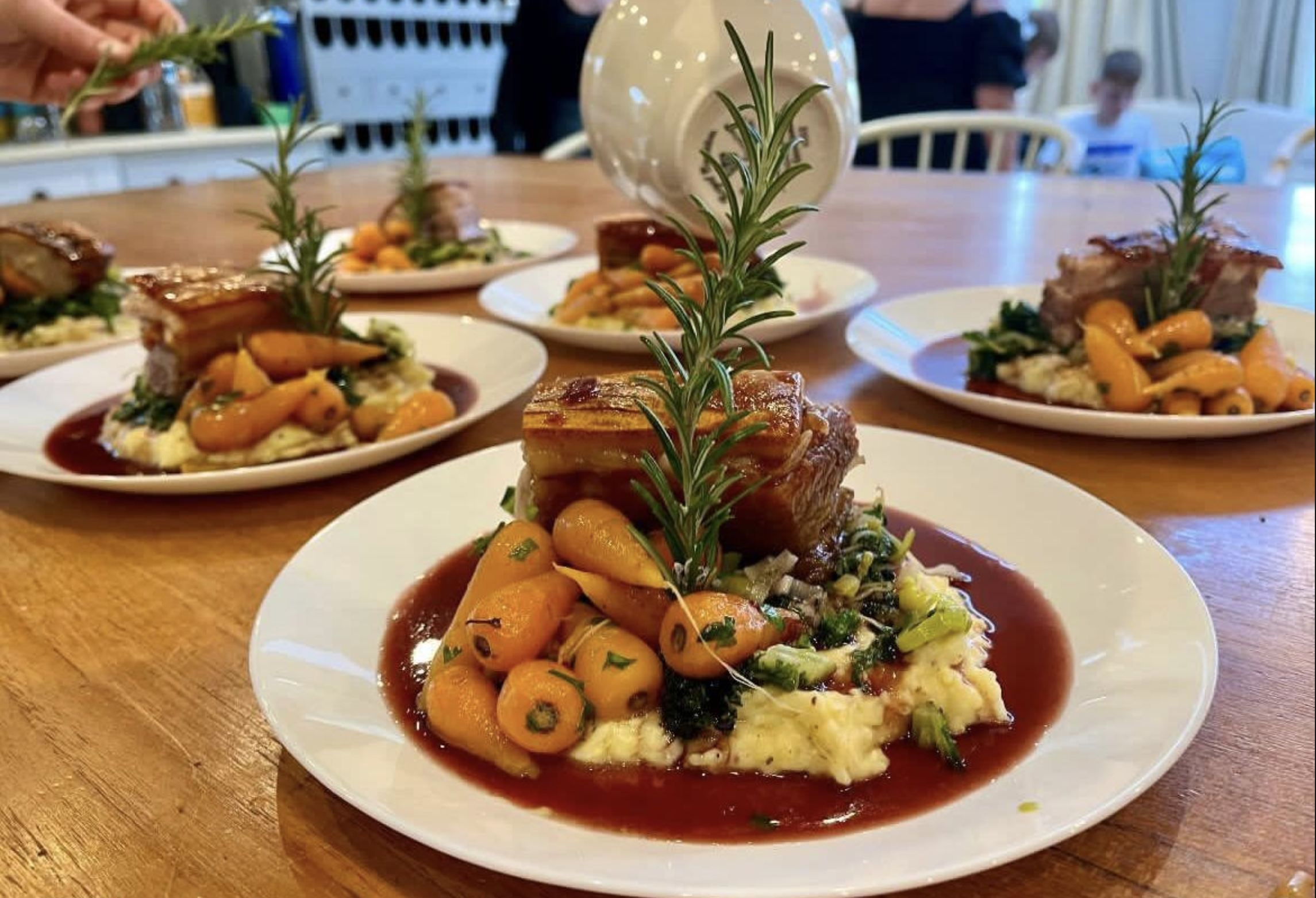 Slow roasted pork belly with rosemary sprigs, carrots and mash