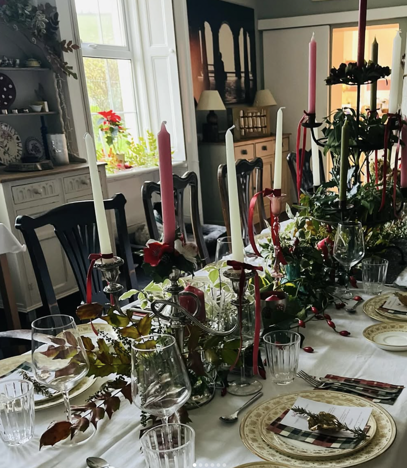 Elegant festive table setting with candles and greenery
